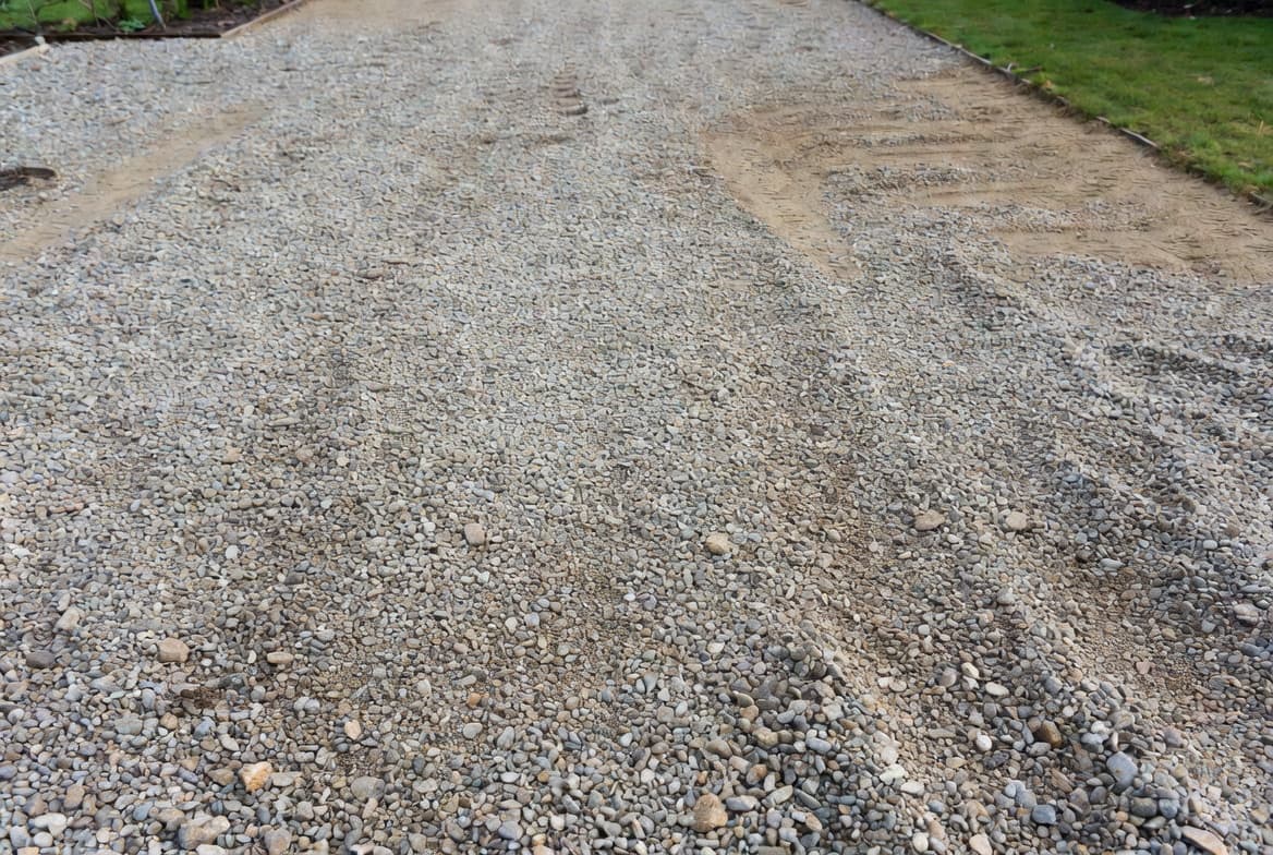 Freshly spread angular crushed stone on a residential gravel driveway surface