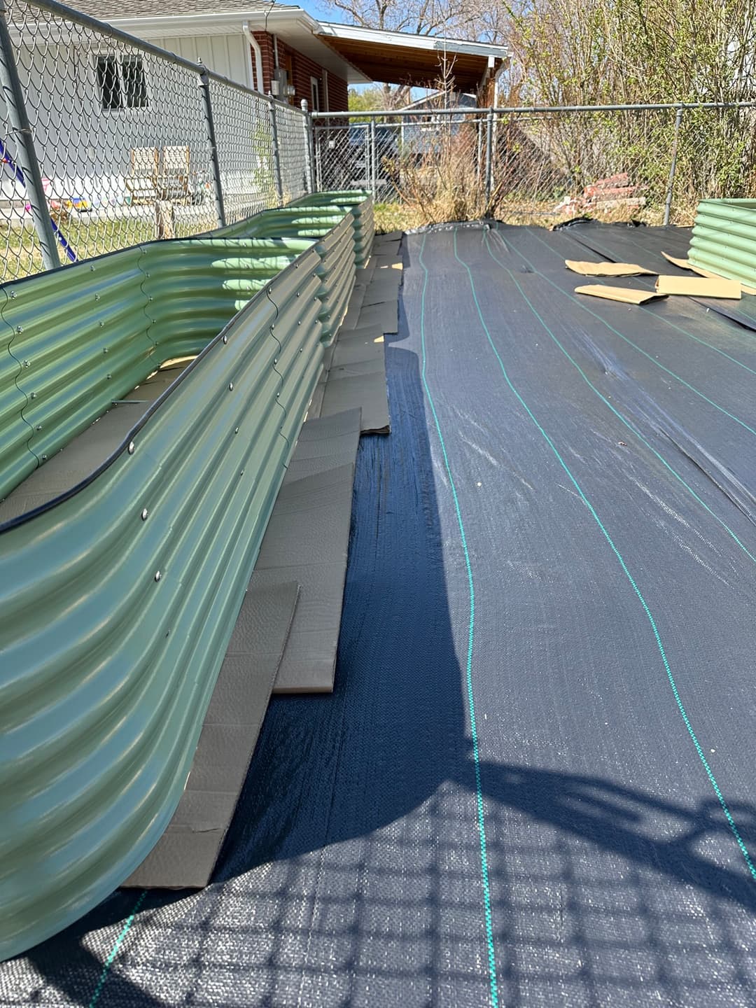 Row of galvanized raised garden beds with landscape fabric and cardboard base, Cody WY